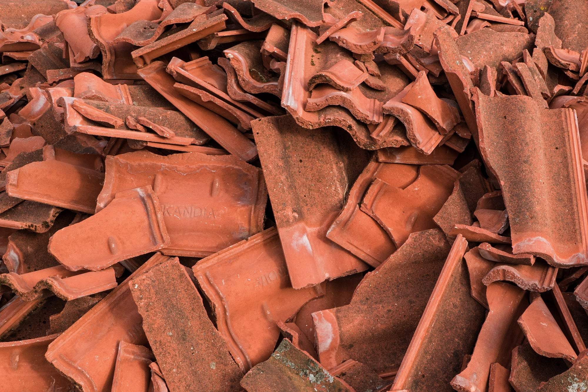 A heap of broken red concrete roof tiles.